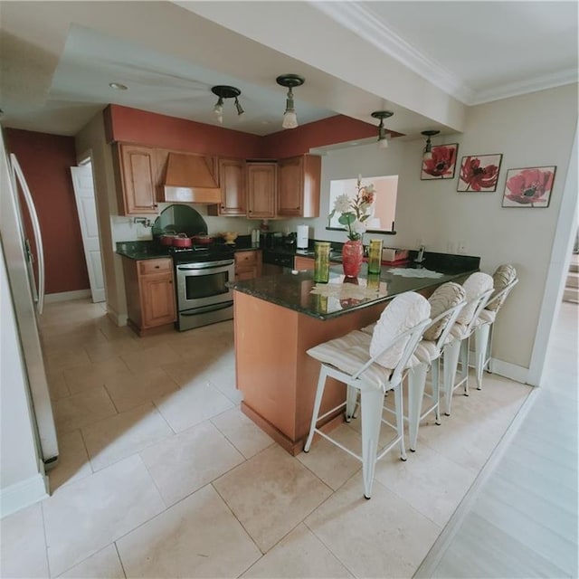 kitchen featuring stainless steel electric range, premium range hood, refrigerator, a kitchen bar, and kitchen peninsula