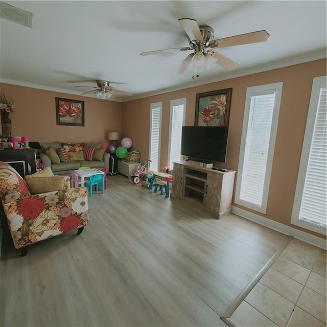 living room with light wood-type flooring, a wealth of natural light, crown molding, and ceiling fan