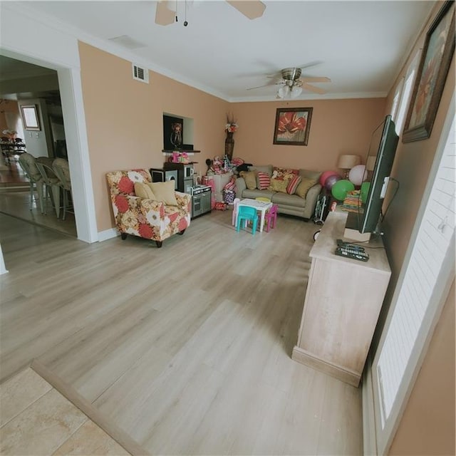 living room with light hardwood / wood-style flooring, ceiling fan, and crown molding