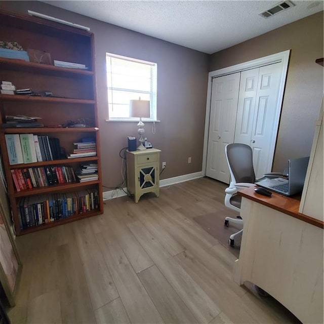 home office featuring light hardwood / wood-style floors and a textured ceiling