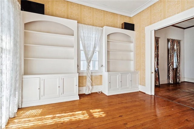 unfurnished dining area with built in shelves, dark hardwood / wood-style floors, and crown molding