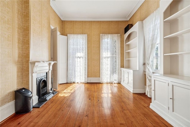 unfurnished living room with built in features, crown molding, and light hardwood / wood-style flooring