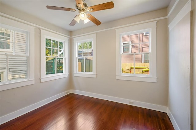 empty room featuring ceiling fan, dark hardwood / wood-style flooring, and a wealth of natural light