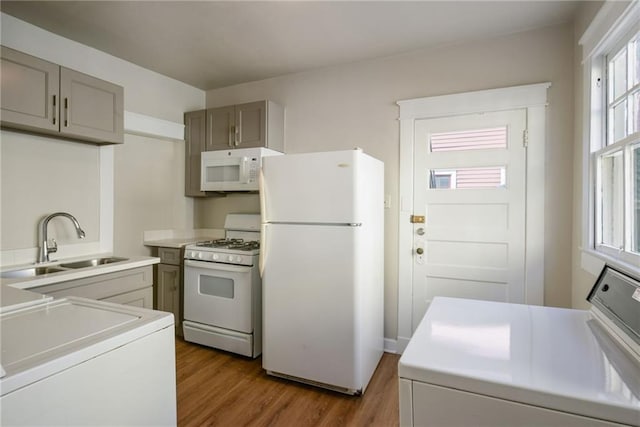 kitchen featuring sink, dark hardwood / wood-style floors, washer / clothes dryer, white appliances, and gray cabinets