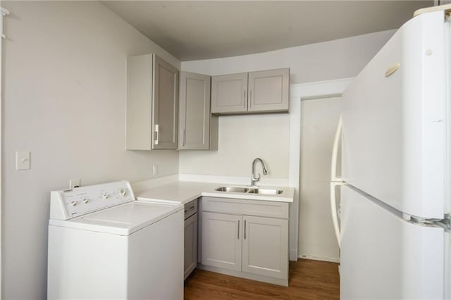 clothes washing area featuring washer / clothes dryer, sink, and dark hardwood / wood-style floors