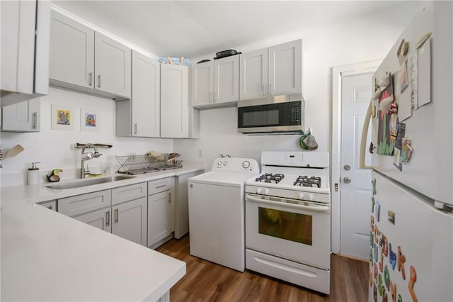 kitchen with sink, dark hardwood / wood-style flooring, white appliances, washer / dryer, and white cabinets