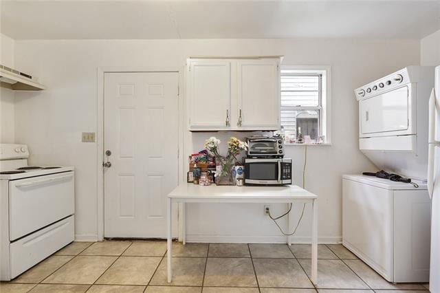 laundry area with light tile patterned floors and stacked washing maching and dryer