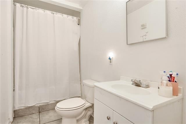 bathroom with toilet, vanity, tile patterned floors, and walk in shower