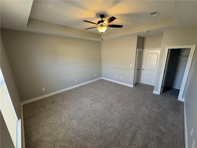 unfurnished bedroom with dark colored carpet, ceiling fan, and a closet