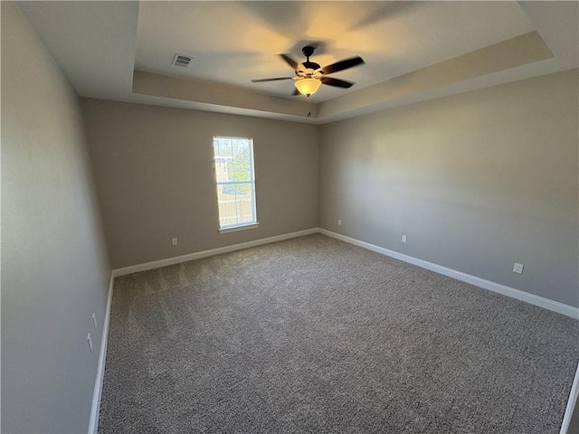 carpeted empty room featuring a raised ceiling and ceiling fan