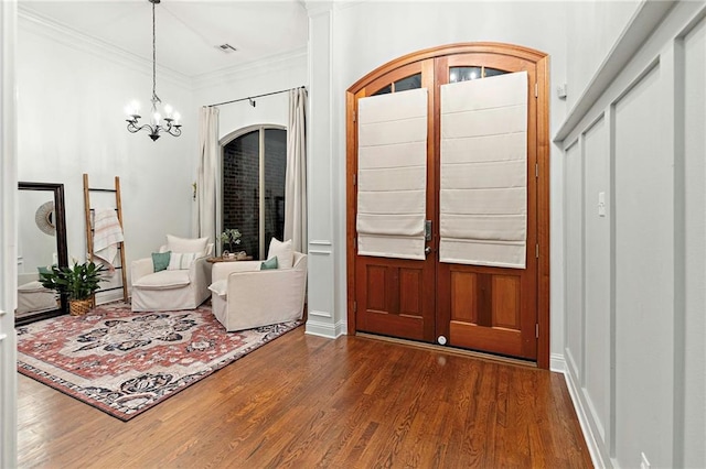 foyer featuring a chandelier, dark hardwood / wood-style floors, and crown molding