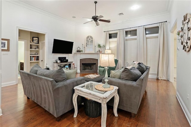 living room featuring built in shelves, hardwood / wood-style flooring, ceiling fan, and ornamental molding