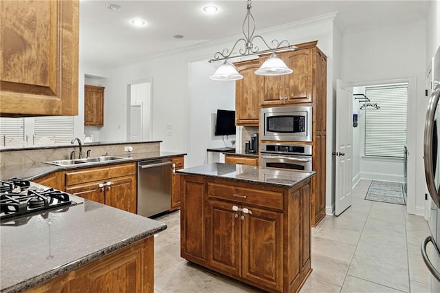 kitchen featuring ornamental molding, stainless steel appliances, sink, pendant lighting, and a kitchen island