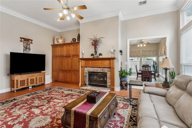 living room featuring crown molding, a healthy amount of sunlight, hardwood / wood-style floors, and a brick fireplace