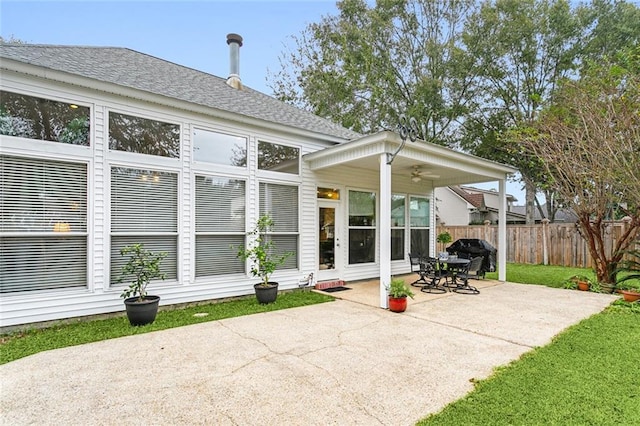 rear view of house featuring ceiling fan, a patio area, and a lawn