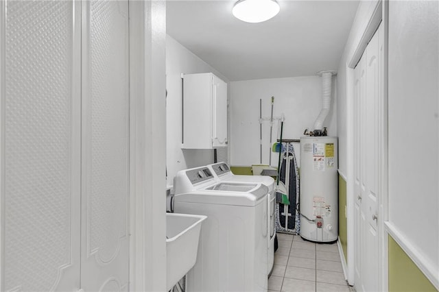 clothes washing area featuring washer and clothes dryer, gas water heater, cabinets, and light tile patterned floors