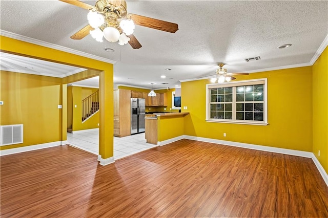 unfurnished living room with ceiling fan, crown molding, light wood-type flooring, and a textured ceiling