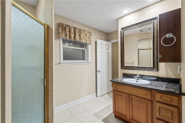 bathroom with a textured ceiling, tile patterned flooring, vanity, and an enclosed shower