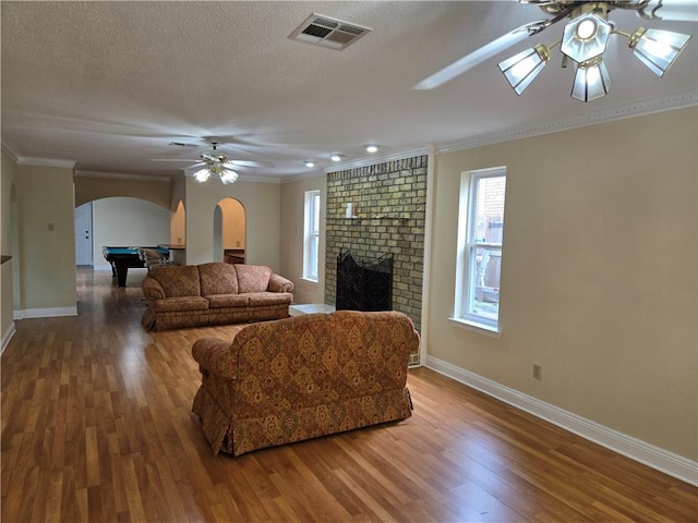 living room featuring a fireplace, wood-type flooring, crown molding, and billiards