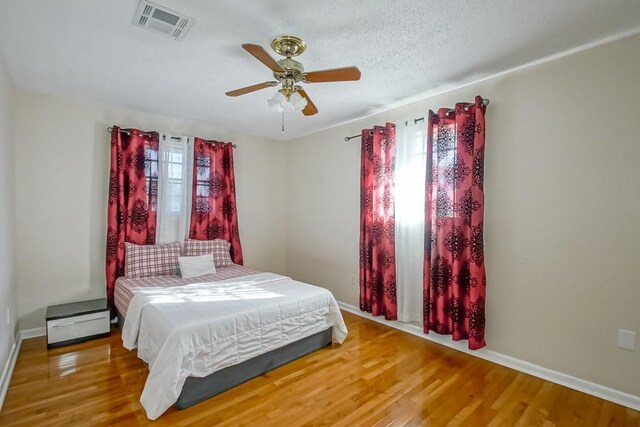 bedroom featuring ceiling fan, a textured ceiling, and hardwood / wood-style flooring