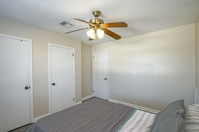 bedroom featuring two closets, ceiling fan, and a textured ceiling