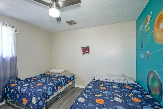 bedroom featuring ceiling fan, hardwood / wood-style floors, and a textured ceiling