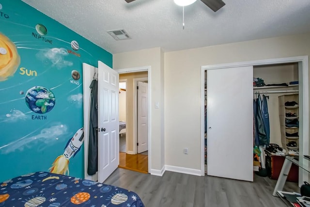 bedroom featuring hardwood / wood-style floors, ceiling fan, a textured ceiling, and a closet