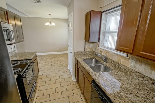 kitchen with decorative backsplash, appliances with stainless steel finishes, sink, pendant lighting, and an inviting chandelier