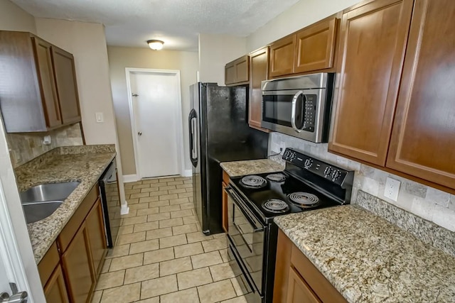 kitchen with backsplash, black appliances, sink, light stone countertops, and light tile patterned floors