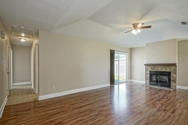 unfurnished living room featuring ceiling fan, a premium fireplace, and dark hardwood / wood-style floors