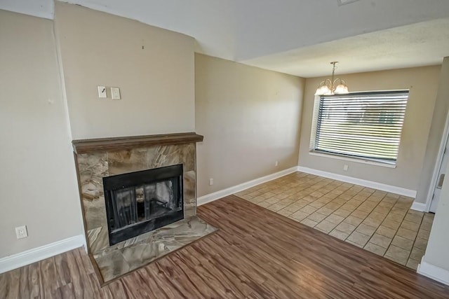 unfurnished living room featuring a fireplace, a chandelier, and hardwood / wood-style flooring