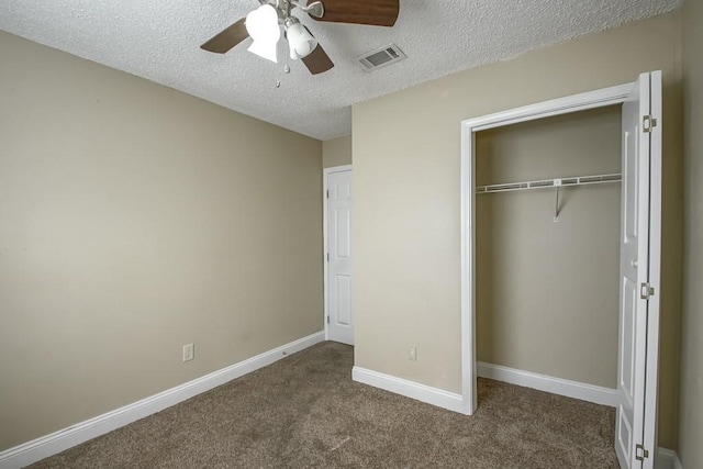 unfurnished bedroom featuring a textured ceiling, a closet, dark carpet, and ceiling fan