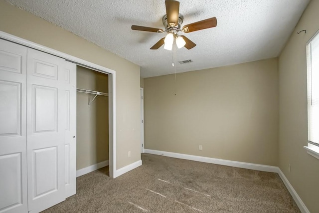 unfurnished bedroom with carpet, a textured ceiling, a closet, and ceiling fan