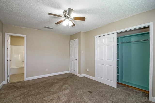 unfurnished bedroom with dark colored carpet, a textured ceiling, ensuite bath, and ceiling fan