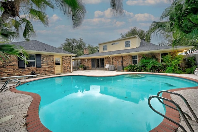 view of pool with central AC unit, a diving board, and a patio