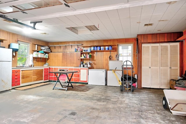 garage with white fridge and wooden walls