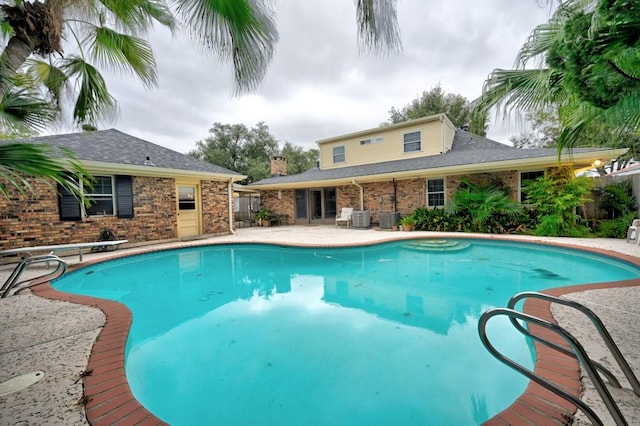 view of pool featuring a diving board, a patio, and central AC unit