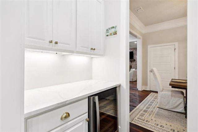 kitchen featuring dark wood-type flooring, light stone countertops, ornamental molding, white cabinetry, and beverage cooler