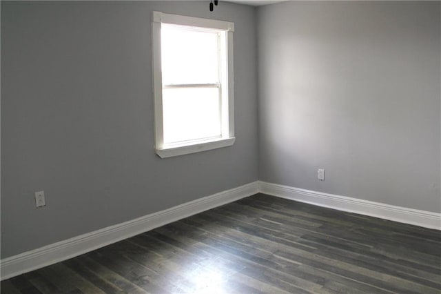 empty room with dark wood-type flooring and a wealth of natural light