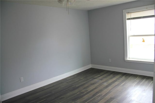 spare room with plenty of natural light and dark wood-type flooring