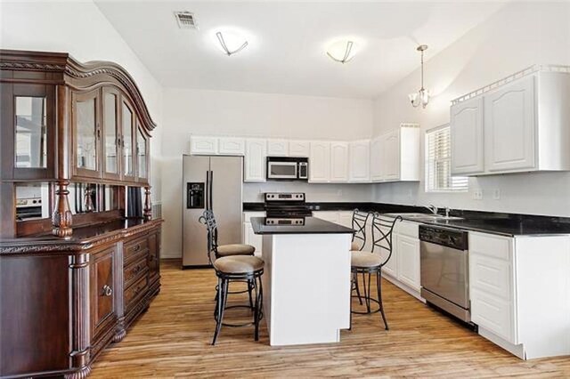 180 Lakeview Dr Unit A, Slidell, LA 70458 - kitchen featuring stainless steel appliances, a kitchen breakfast bar, dark countertops, white cabinets, and light wood-style floors