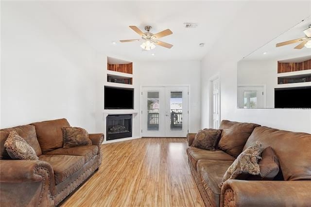 living room with ceiling fan, light hardwood / wood-style floors, built in features, and french doors