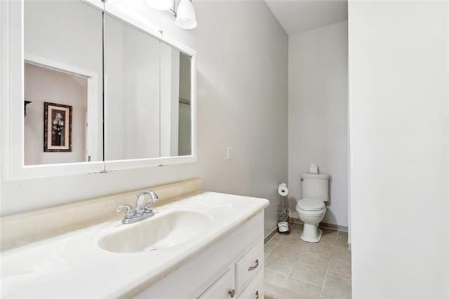 bathroom with toilet, vanity, and tile patterned floors