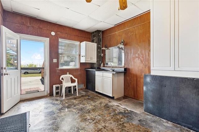 180 Lakeview Dr Unit A, Slidell, LA 70458 - kitchen with wooden walls, white cabinetry, a sink, and concrete flooring