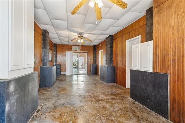 hall featuring wooden walls and concrete floors