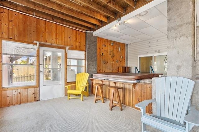 sitting room featuring beamed ceiling, carpet floors, a jacuzzi, and wooden walls