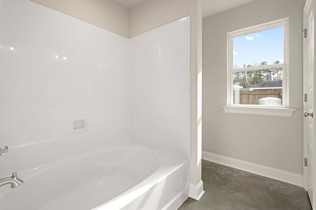 bathroom featuring concrete flooring and a bath