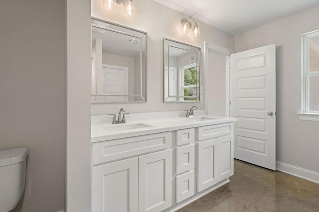 bathroom with vanity, toilet, and concrete floors