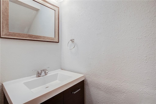 bathroom with a textured wall and vanity