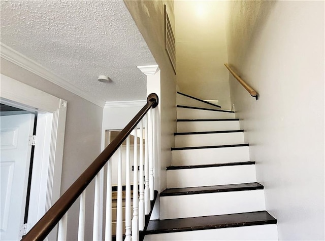 stairs featuring a textured ceiling and crown molding